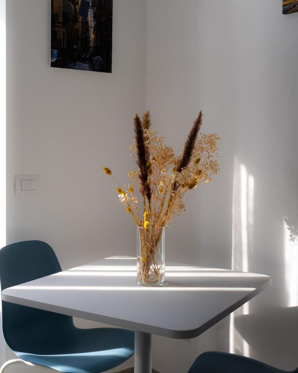um vaso de flores numa mesa branca com duas cadeiras azuis em Dimora Cavour em Nápoles