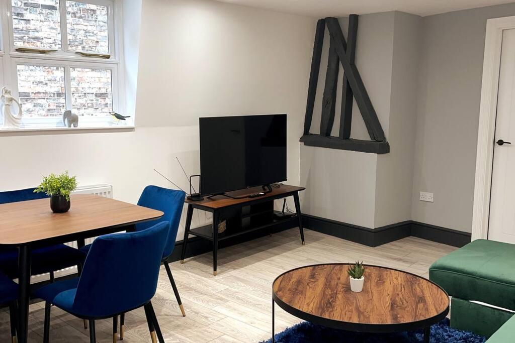 a living room with a table and a tv at Abacus House - TWO Bedroom Apartment in Huntingdon