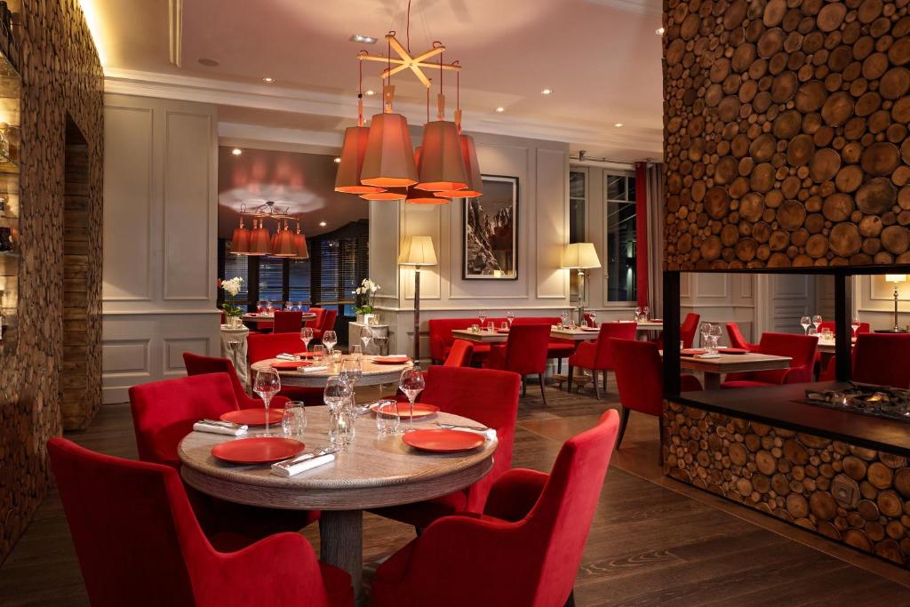 a dining room with red chairs and a table in a restaurant at Hôtel Mont-Blanc Chamonix in Chamonix