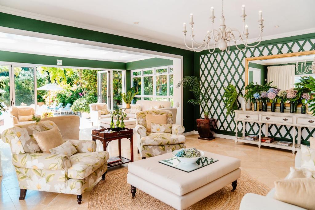 uma sala de estar com mobiliário branco e paredes verdes em Last Word Constantia em Cidade do Cabo