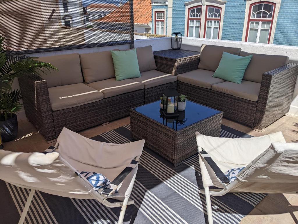 a patio with a couch and two chairs and a table at the light house in Vila Real de Santo António