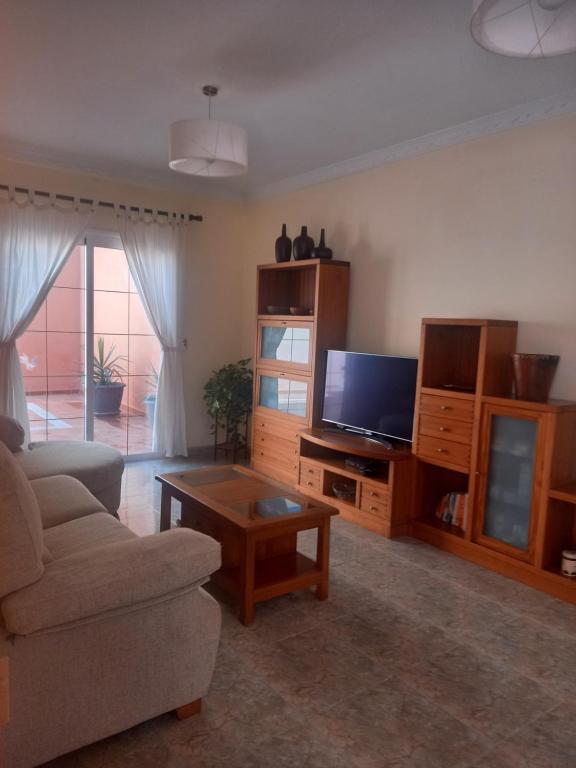 ein Wohnzimmer mit einem Sofa, einem TV und einem Tisch in der Unterkunft Casa Islas 1 in Ingenio
