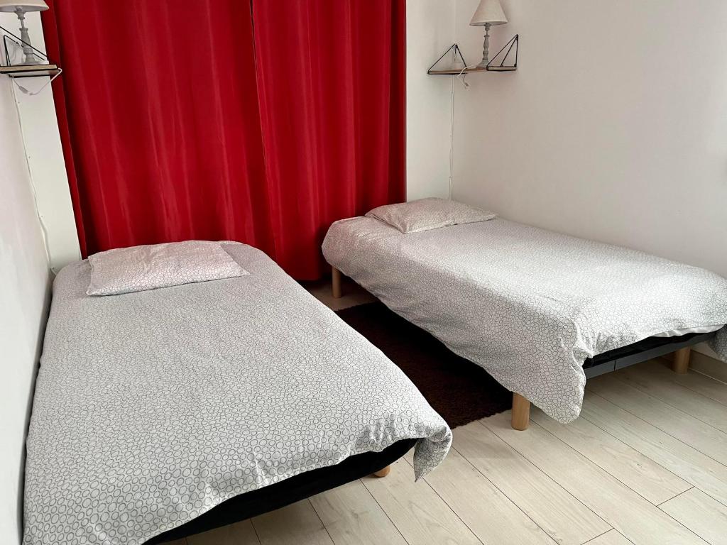 - 2 lits dans une chambre avec rideau rouge dans l'établissement L'Ostréa, maison avec jardin à 200m de la mer-wifi, à Saint-Côme-de-Fresné
