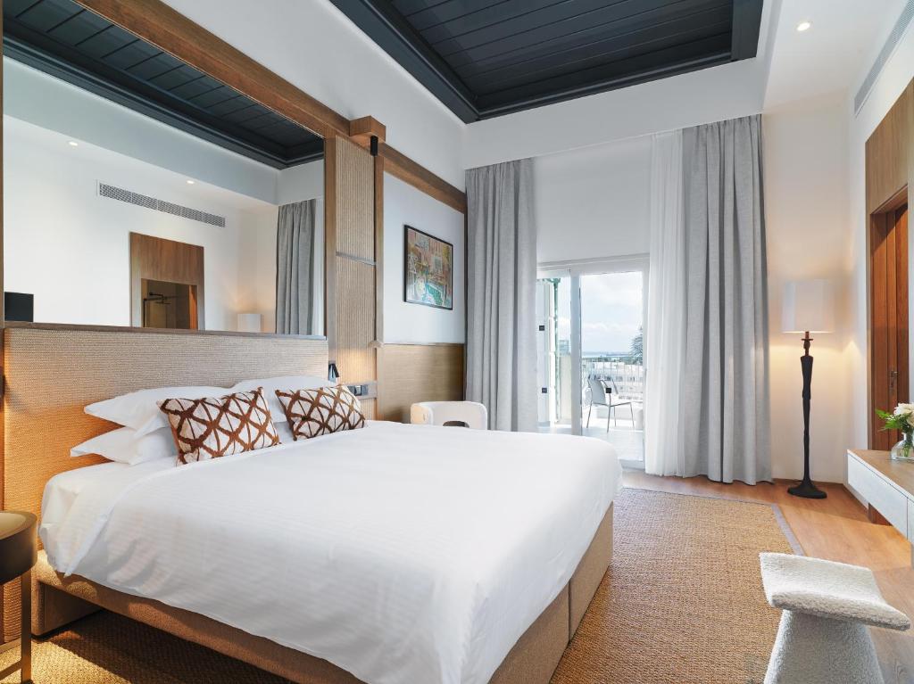 a bedroom with a large bed and a large window at Leonardo Boutique Hotel Larnaca in Larnaca
