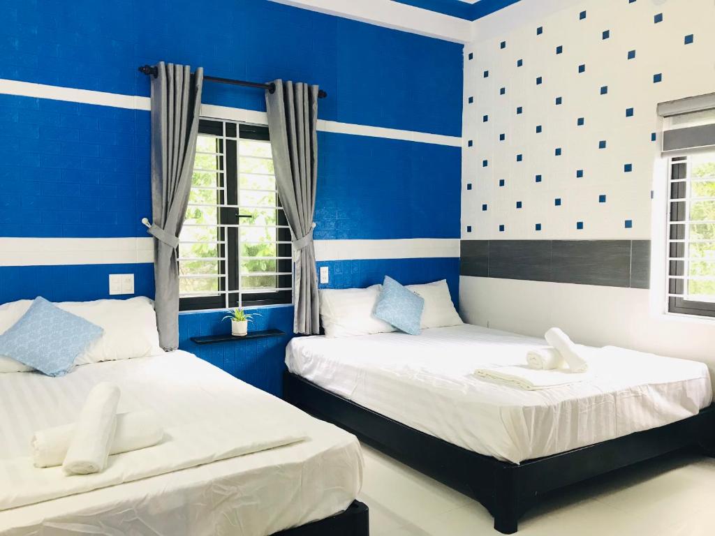 two beds in a room with blue walls and windows at Monkeyland Cham island Homestay in Tân Hiệp
