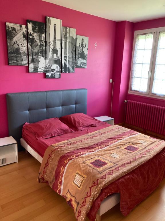 1 dormitorio con paredes rosas y 1 cama con sábanas rojas en Chez Bernard pavillon proche Disneyland et Paris, en Coulommiers