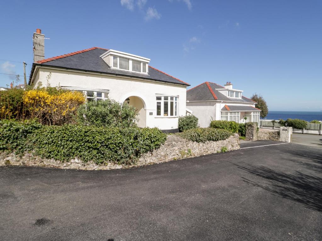 a white house with the ocean in the background at The Nook in Benllech