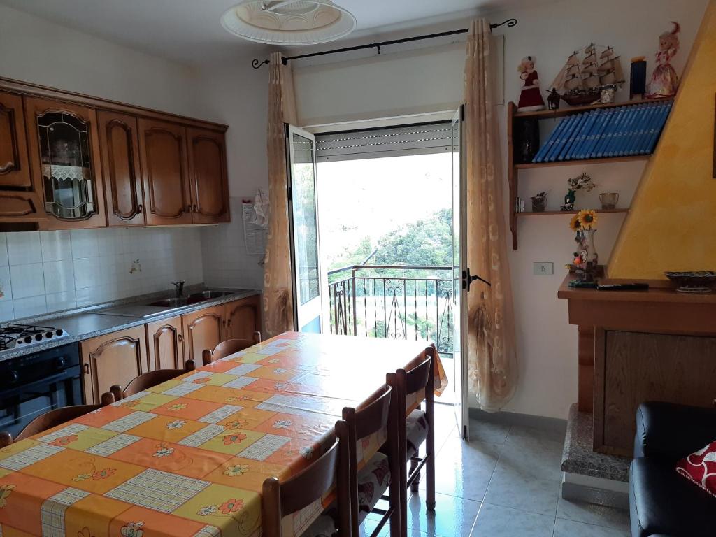una cucina con tavolo, sedie e ampia finestra di DESULO casa vacanze a Desulo