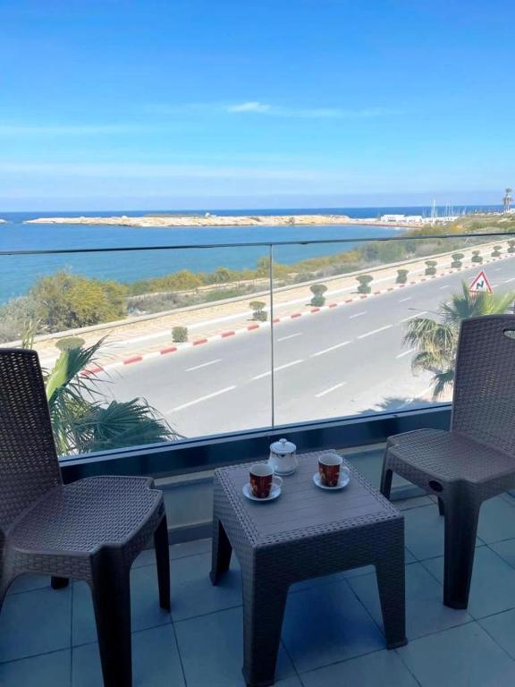 - un balcon avec deux chaises et une table avec deux tasses dans l'établissement Studio avec vue directe mer, à Monastir