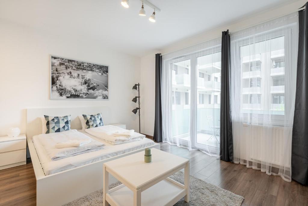 een witte woonkamer met een bed en een tafel bij White Cottage Studio in Boedapest