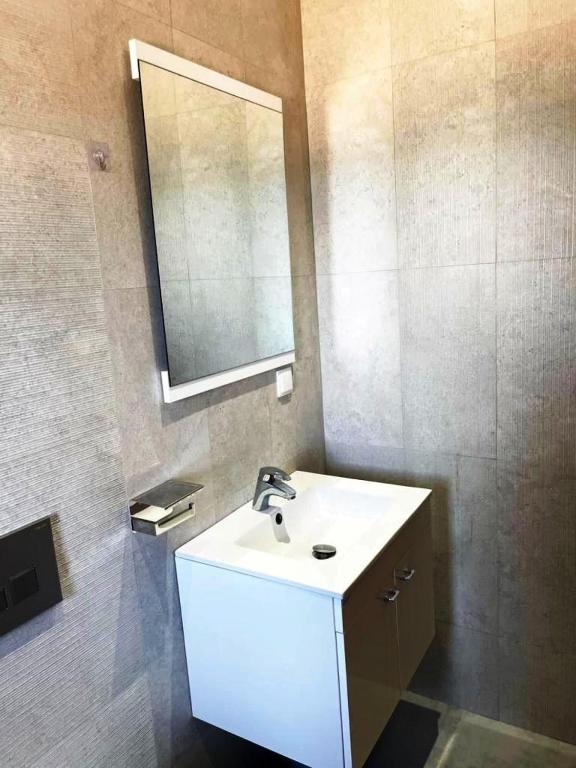 La salle de bains est pourvue d'un lavabo blanc et d'un miroir. dans l'établissement Studio avec vue directe mer, à Monastir