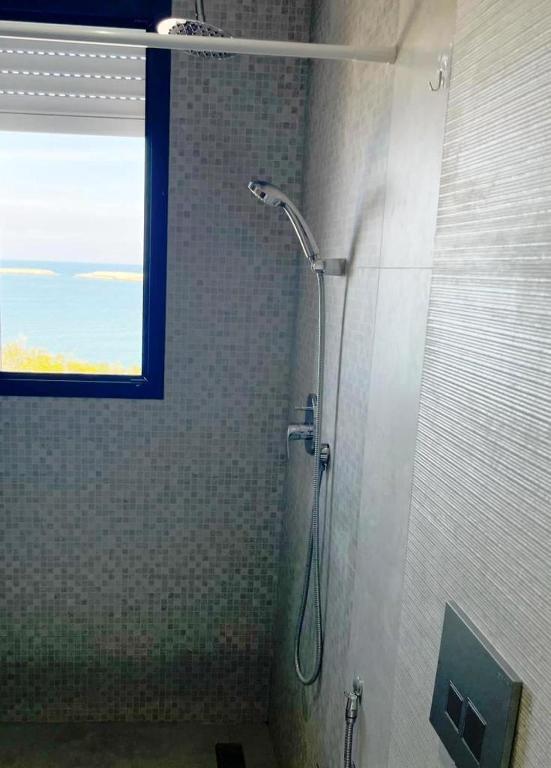 La salle de bains est pourvue d'une cabine de douche et d'une fenêtre. dans l'établissement Studio avec vue directe mer, à Monastir