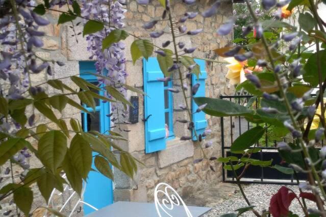 ein Gebäude mit blauen Fenstern und Blumen davor in der Unterkunft abri du marin in Séné