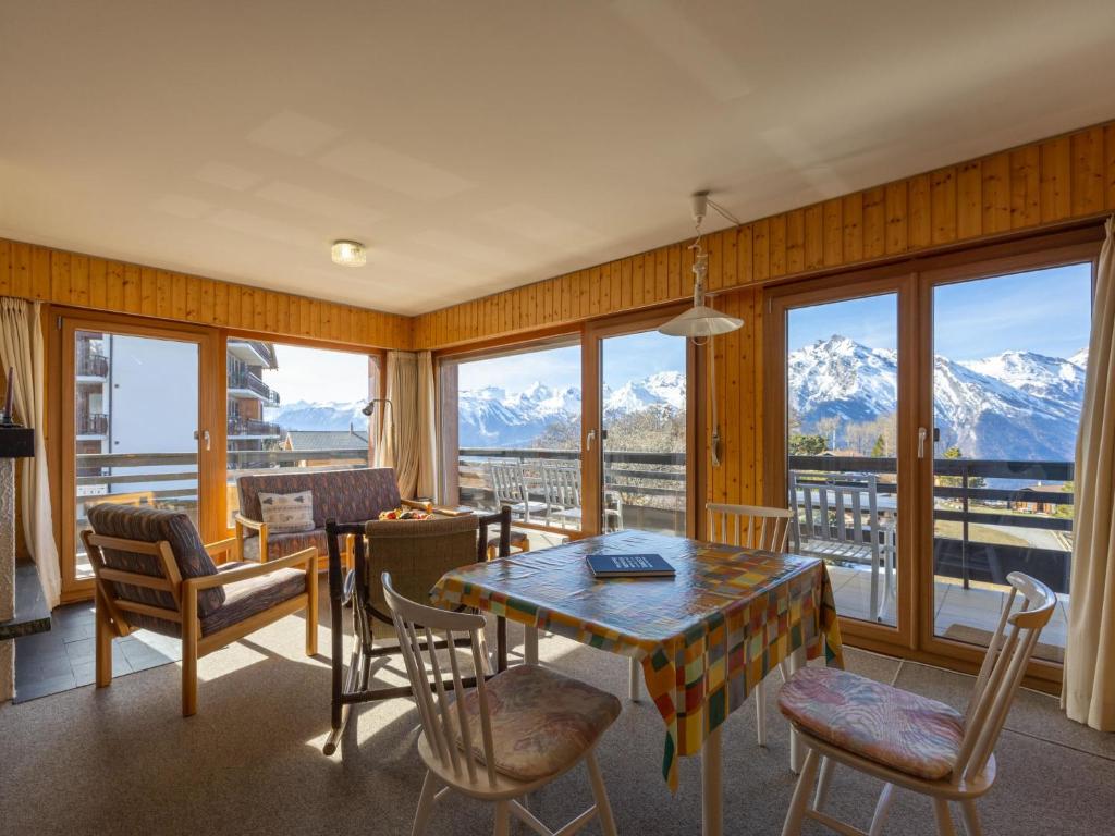 a dining room with a table and chairs and mountains at Apartment Muverans I L2 by Interhome in Nendaz