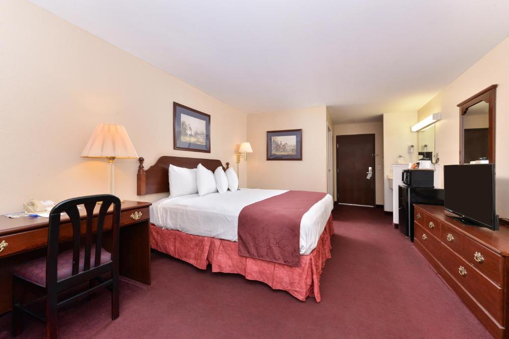 ein Hotelzimmer mit einem Bett, einem Schreibtisch und einem TV in der Unterkunft Americas Best Value Inn Somerville Texas in Somerville