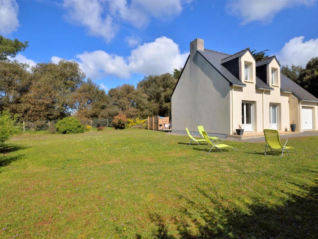a house with two lawn chairs in the yard at Holiday Home Les Chênes Verts - LTB310 by Interhome in La Turballe