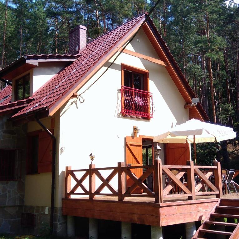 a small house with a balcony and an umbrella at Cztery Pory Lasu in Silna Nowa