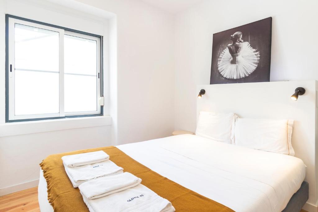 - une chambre avec un lit doté de draps blancs et une fenêtre dans l'établissement Gloria 10, à Lisbonne