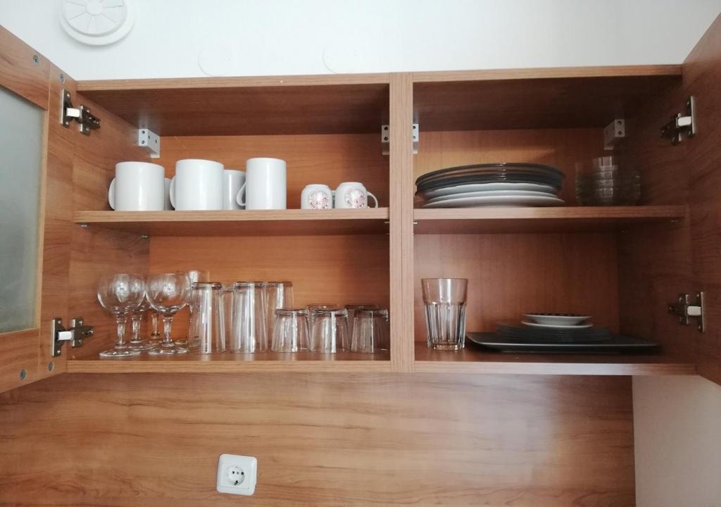 a cupboard with plates and glasses and dishes at Charis Cozy Family apart at Sun Village Complex close to the Beach in Sunny Beach