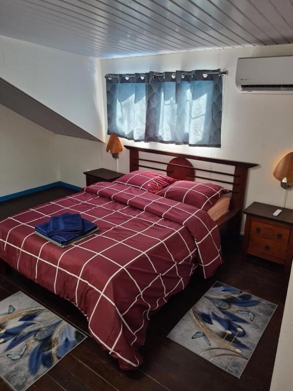 ein Schlafzimmer mit einem Bett mit einer roten Bettdecke und einem Fenster in der Unterkunft Résidence JB in Sinnamary