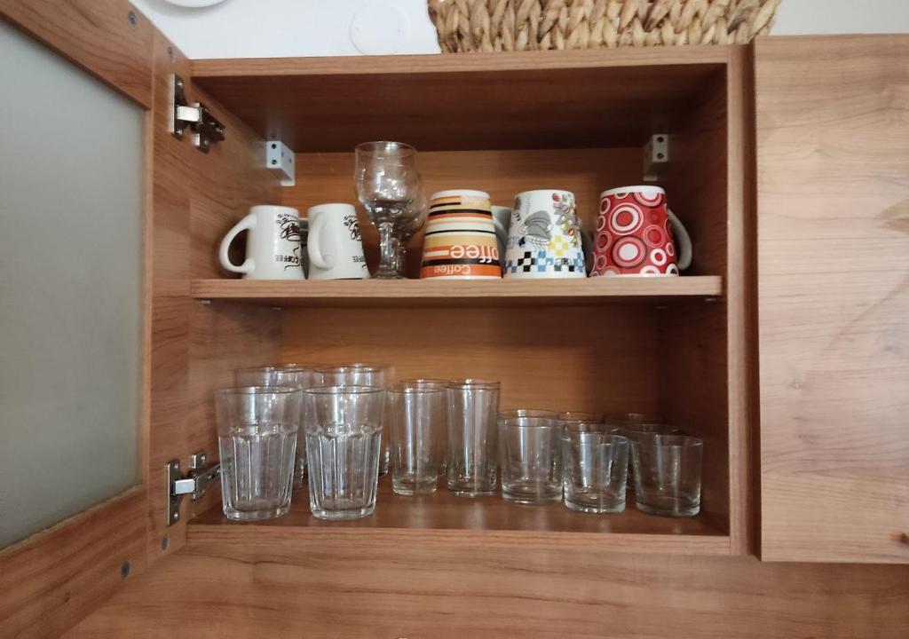 a cupboard with glasses and mugs in it at Charis Cozy Family apart at Sun Village Complex close to the Beach in Sunny Beach