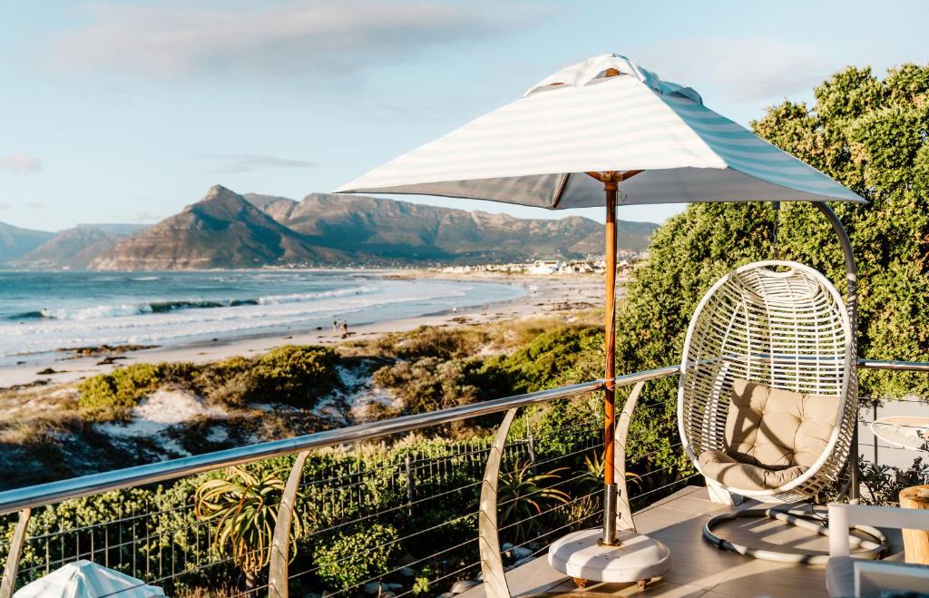 a balcony with an umbrella and chairs and a beach at Last Word Long Beach in Kommetjie