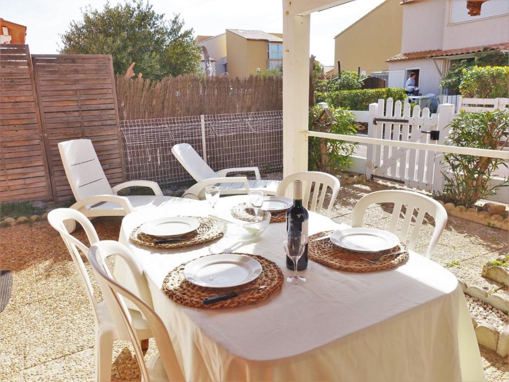 una mesa con mantel blanco y sillas blancas en Holiday Home Les Balcons de la Méditerranée-26 by Interhome, en Narbonne-Plage