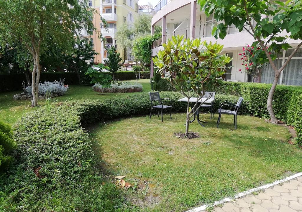 a park with chairs and a table and a tree at Charis Cozy Family apart at Sun Village Complex close to the Beach in Sunny Beach