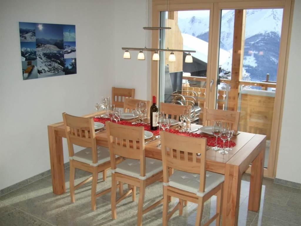 tavolo da pranzo con sedie e bottiglia di vino di Apartment Amici 1- Stock Allegra by Interhome a Riederalp