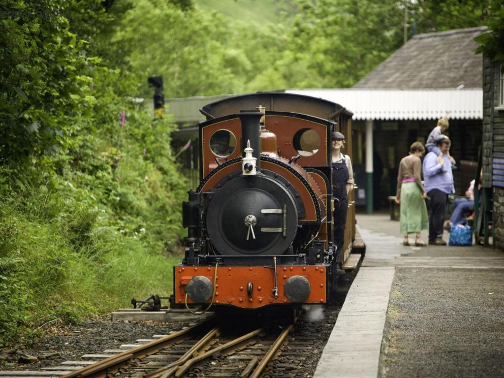 a train pulling into a station with people on the tracks at Holiday Home Pa by Interhome in Machynlleth