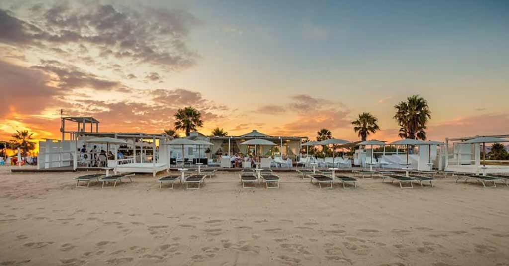 a beach with chairs and umbrellas at sunset at ### Appartamenti sulla SPIAGGIA al POETTO ### in Cagliari