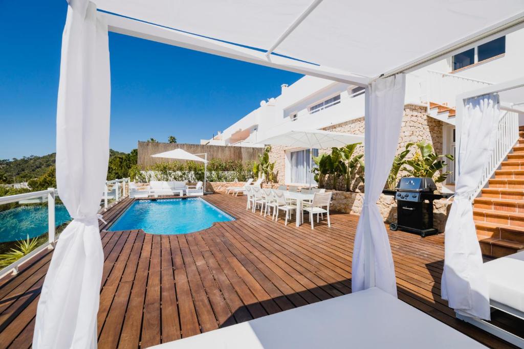 una terraza de madera con piscina y una casa en Villa Serretes, en Cala Vadella