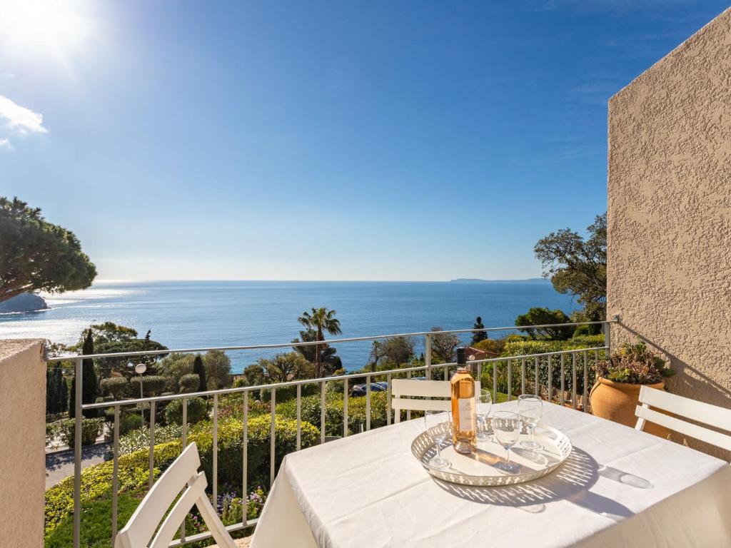 a table with a bottle of wine on a balcony with the ocean at Apartment Le Paradou-4 by Interhome in Rayol-Canadel-sur-Mer
