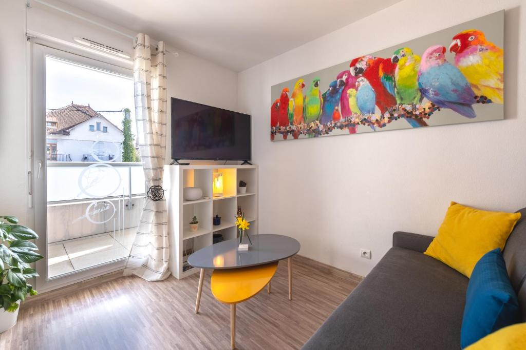 Sala de estar con sofá y loros en la pared en Studio Cosy les Perruches, en Thonon-les-Bains