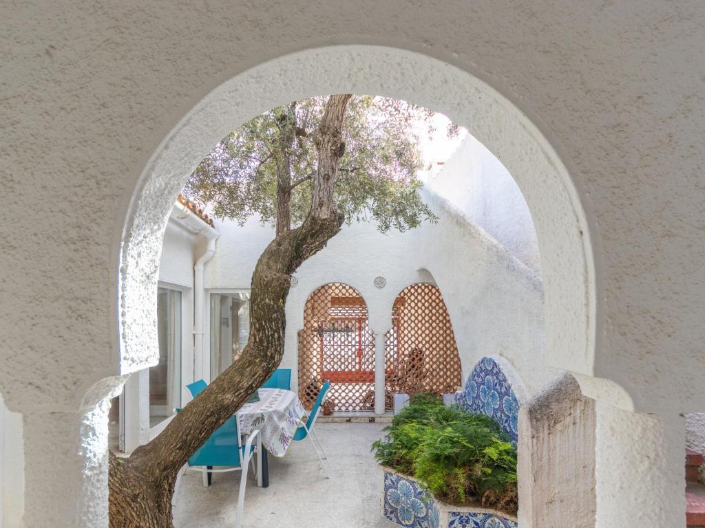 einen Torbogen mit Stühlen, einem Tisch und einem Baum in der Unterkunft Holiday Home Los Abuelos by Interhome in Cambrils