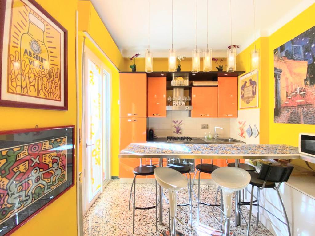 cocina con paredes amarillas y encimera con taburetes en Pisa Happy House 5, en Pisa