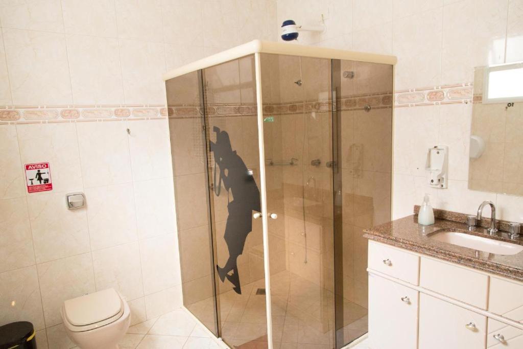 a bathroom with a glass shower with a toilet at Joshua Tree Hostel - Curitiba in Curitiba