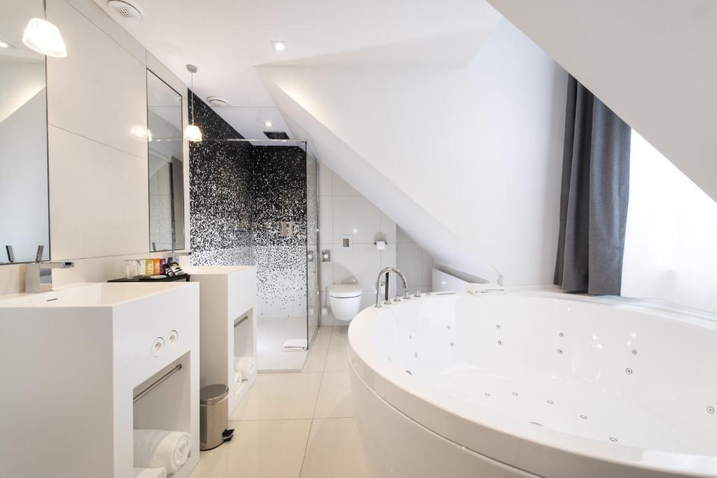 a white bathroom with a large tub and a sink at Vertigo Hotel, By Marriott, a Member of Design Hotels in Dijon