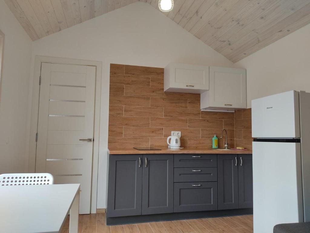 eine Küche mit grauen Schränken und einem weißen Kühlschrank in der Unterkunft house for relaxation in Kriukivshchyna