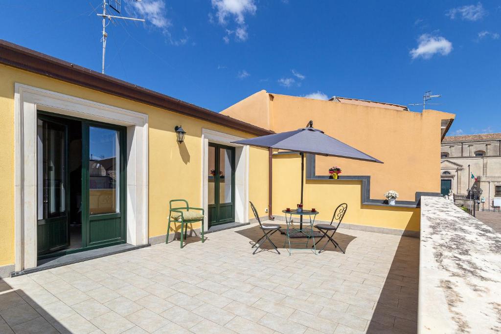 une terrasse avec une table et un parasol dans l'établissement Belvedere 3, à Piedimonte Etneo