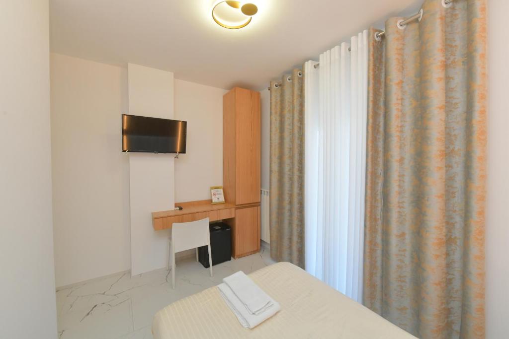Pokój z łóżkiem, biurkiem i telewizorem w obiekcie Noemi B&B w mieście Modugno