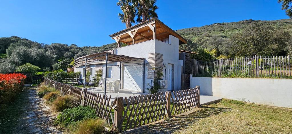 une petite maison blanche avec une clôture en bois dans l'établissement Mini villa T2 climatisée, vue mer, cosy & moderne, à Olmeto