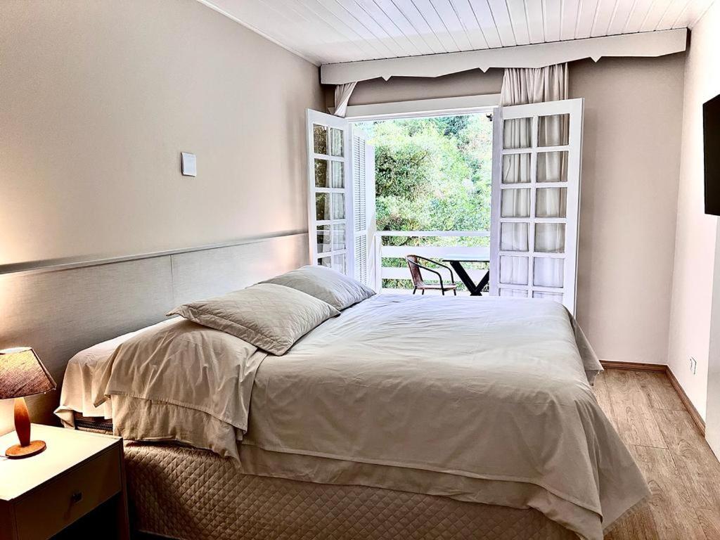 Un dormitorio con una cama grande y una ventana en Pousada Morro do Elefante, en Campos do Jordão