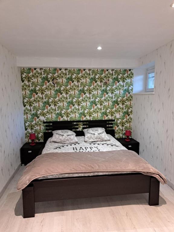 - une chambre avec un grand lit et un mur fleuri dans l'établissement Gîtes du Bois de Bontemps, à Sarlat-la-Canéda
