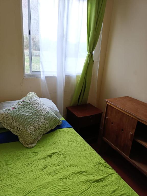 a bedroom with a green bed and a window at Huerto El Tránsito in El Portillo