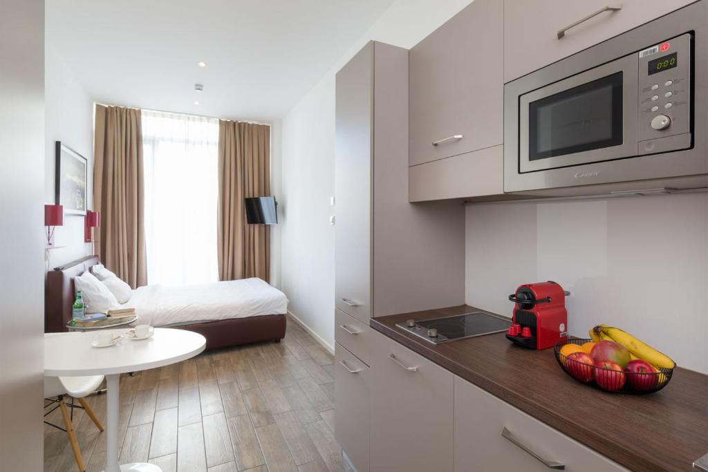 um quarto com uma cama e uma cozinha com um micro-ondas em Brera Serviced Apartments Munich West em Munique