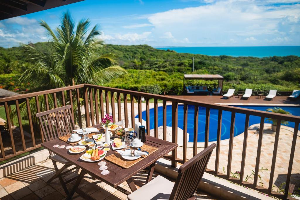 a table with food on a balcony with a view of the ocean at Oka Da Mata in Pipa