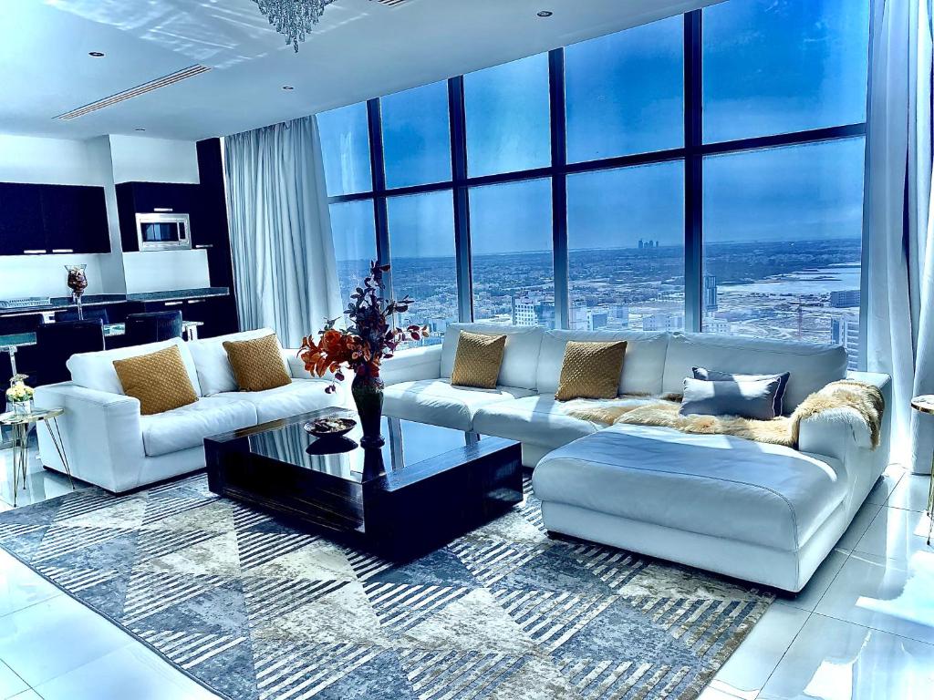 Skyline Apartments في المنامة: غرفة معيشة بأثاث أبيض ونوافذ كبيرة