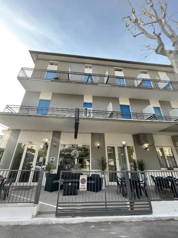 un edificio con balcone arredato con tavoli e sedie di Hotel villa del bagnino a Rimini