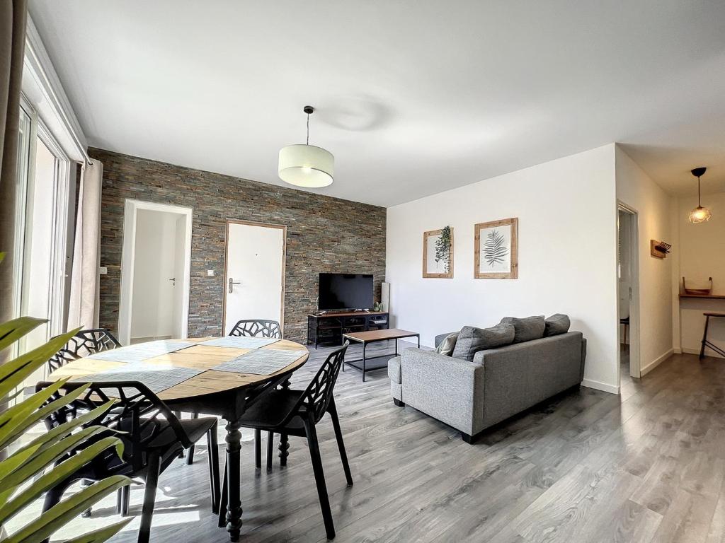 ein Wohnzimmer mit einem Tisch und einem Sofa in der Unterkunft Appart T3 LE PATIO - avec terrasse in Boujan-sur-Libron